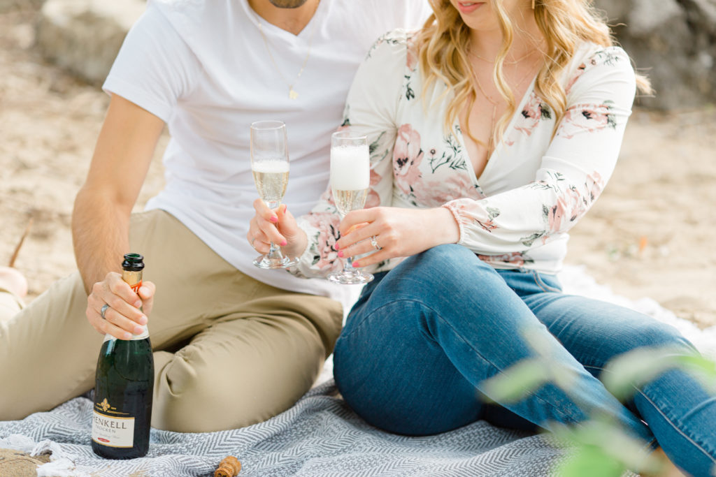 Sitting on the Beach - Ideas for what to wear for Engagement Photography, Modern Engagement Session Inspiration Wardrobe Ideas. Unsure of what to wear for your engagement photos, we've got you! Romantic floral shirt & jeans.  White T-shirt & neutral pants . Boat Shoes and Fancy. beaded sandals. Engagement at Petrie Island, Orleans. Grey Loft Studio is Ottawa's Wedding and Engagement Photographer Videographer for Real couples, showcasing photos that are modern, bright, and fun.