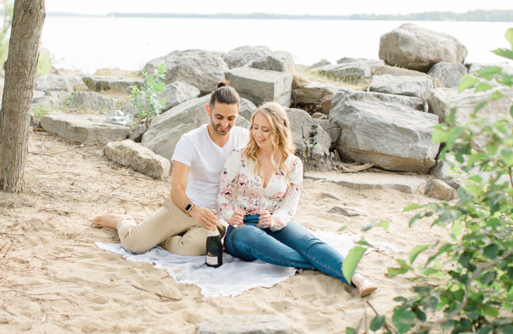 Sitting on the Beach - Ideas for what to wear for Engagement Photography, Modern Engagement Session Inspiration Wardrobe Ideas. Unsure of what to wear for your engagement photos, we've got you! Romantic floral shirt & jeans.  White T-shirt & neutral pants . Boat Shoes and Fancy. beaded sandals. Engagement at Petrie Island, Orleans. Grey Loft Studio is Ottawa's Wedding and Engagement Photographer Videographer for Real couples, showcasing photos that are modern, bright, and fun.
