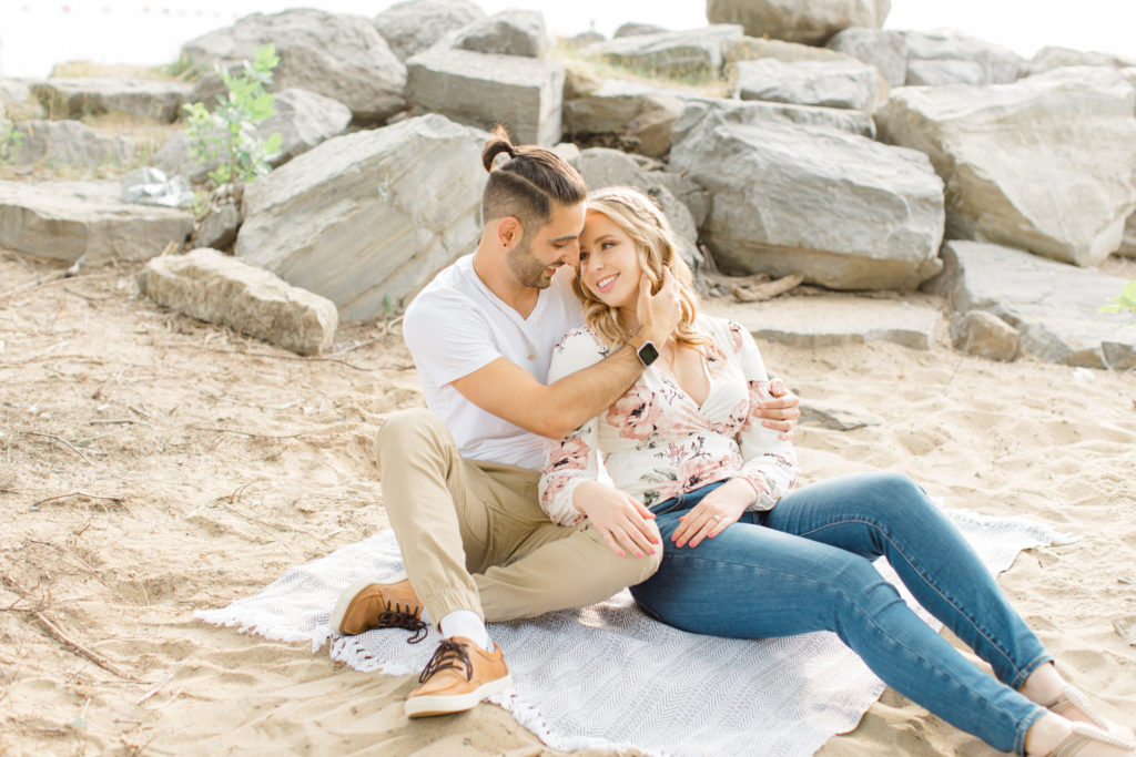 Sitting on the Beach - Ideas for what to wear for Engagement Photography, Modern Engagement Session Inspiration Wardrobe Ideas. Unsure of what to wear for your engagement photos, we've got you! Romantic floral shirt & jeans.  White T-shirt & neutral pants . Boat Shoes and Fancy. beaded sandals. Engagement at Petrie Island, Orleans. Grey Loft Studio is Ottawa's Wedding and Engagement Photographer Videographer for Real couples, showcasing photos that are modern, bright, and fun.