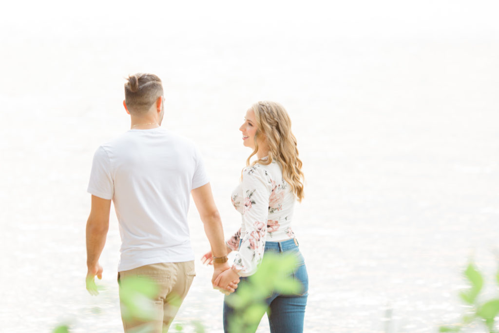 Walking on the Beach - Ideas for what to wear for Engagement Photography, Modern Engagement Session Inspiration Wardrobe Ideas. Unsure of what to wear for your engagement photos, we've got you! Romantic floral shirt & jeans.  White T-shirt & neutral pants . Boat Shoes and Fancy. beaded sandals. Engagement at Petrie Island, Orleans. Grey Loft Studio is Ottawa's Wedding and Engagement Photographer Videographer for Real couples, showcasing photos that are modern, bright, and fun.