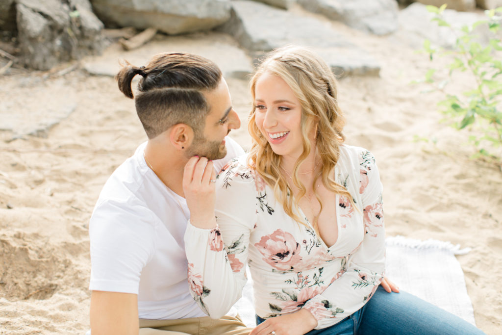 Sitting on the Beach - Ideas for what to wear for Engagement Photography, Modern Engagement Session Inspiration Wardrobe Ideas. Unsure of what to wear for your engagement photos, we've got you! Romantic floral shirt & jeans.  White T-shirt & neutral pants . Boat Shoes and Fancy. beaded sandals. Engagement at Petrie Island, Orleans. Grey Loft Studio is Ottawa's Wedding and Engagement Photographer Videographer for Real couples, showcasing photos that are modern, bright, and fun.
