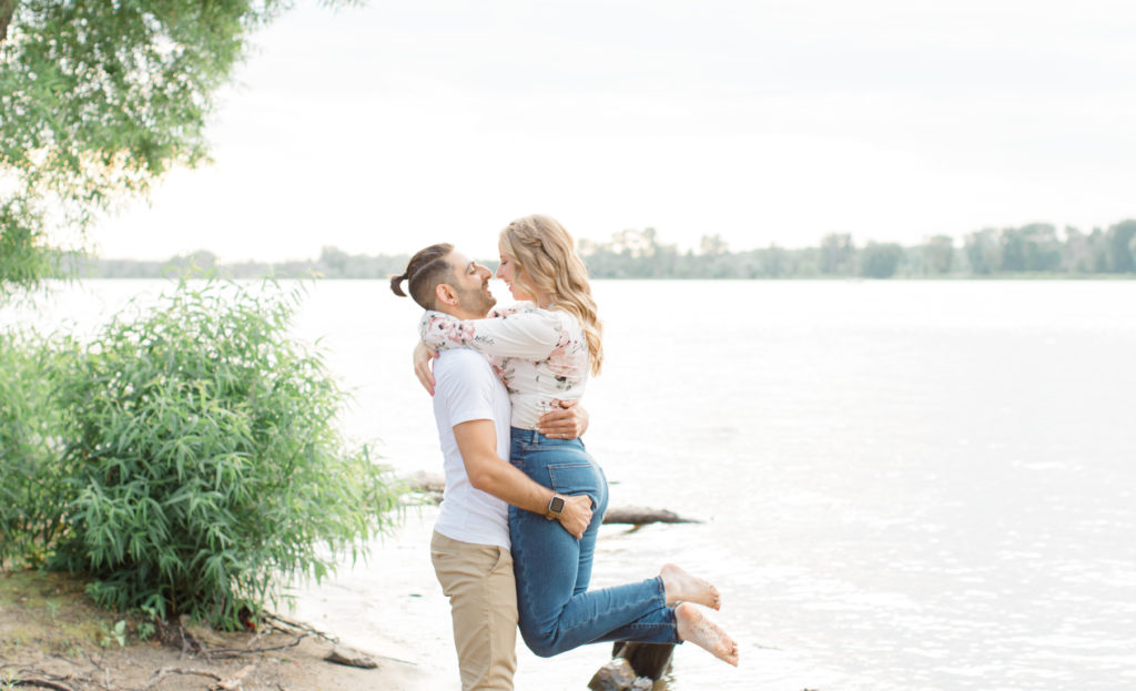 Lifting on the beach - Ideas for what to wear for Engagement Photography, Modern Engagement Session Inspiration Wardrobe Ideas. Unsure of what to wear for your engagement photos, we've got you! Romantic floral shirt & jeans.  White T-shirt & neutral pants . Boat Shoes and Fancy. beaded sandals. Engagement at Petrie Island, Orleans. Grey Loft Studio is Ottawa's Wedding and Engagement Photographer Videographer for Real couples, showcasing photos that are modern, bright, and fun.