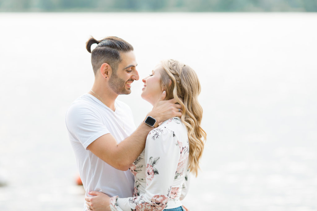 Kissing on the beach - Ideas for what to wear for Engagement Photography, Modern Engagement Session Inspiration Wardrobe Ideas. Unsure of what to wear for your engagement photos, we've got you! Romantic floral shirt & jeans.  White T-shirt & neutral pants . Boat Shoes and Fancy. beaded sandals. Engagement at Petrie Island, Orleans. Grey Loft Studio is Ottawa's Wedding and Engagement Photographer Videographer for Real couples, showcasing photos that are modern, bright, and fun.