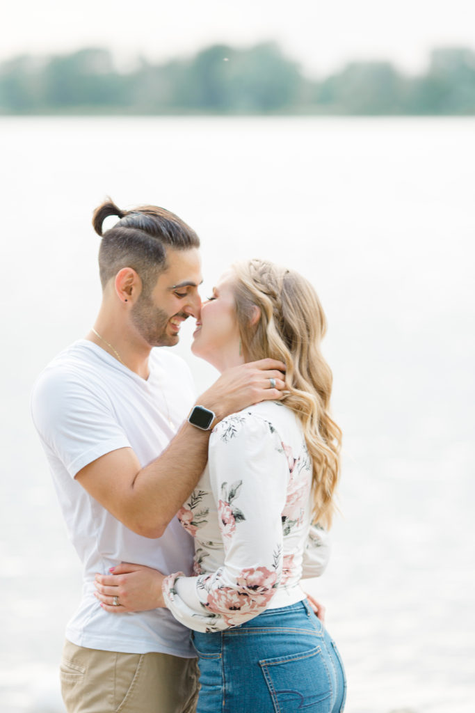 Nose to Nose on the beach - Ideas for what to wear for Engagement Photography, Modern Engagement Session Inspiration Wardrobe Ideas. Unsure of what to wear for your engagement photos, we've got you! Romantic floral shirt & jeans.  White T-shirt & neutral pants . Boat Shoes and Fancy. beaded sandals. Engagement at Petrie Island, Orleans. Grey Loft Studio is Ottawa's Wedding and Engagement Photographer Videographer for Real couples, showcasing photos that are modern, bright, and fun.