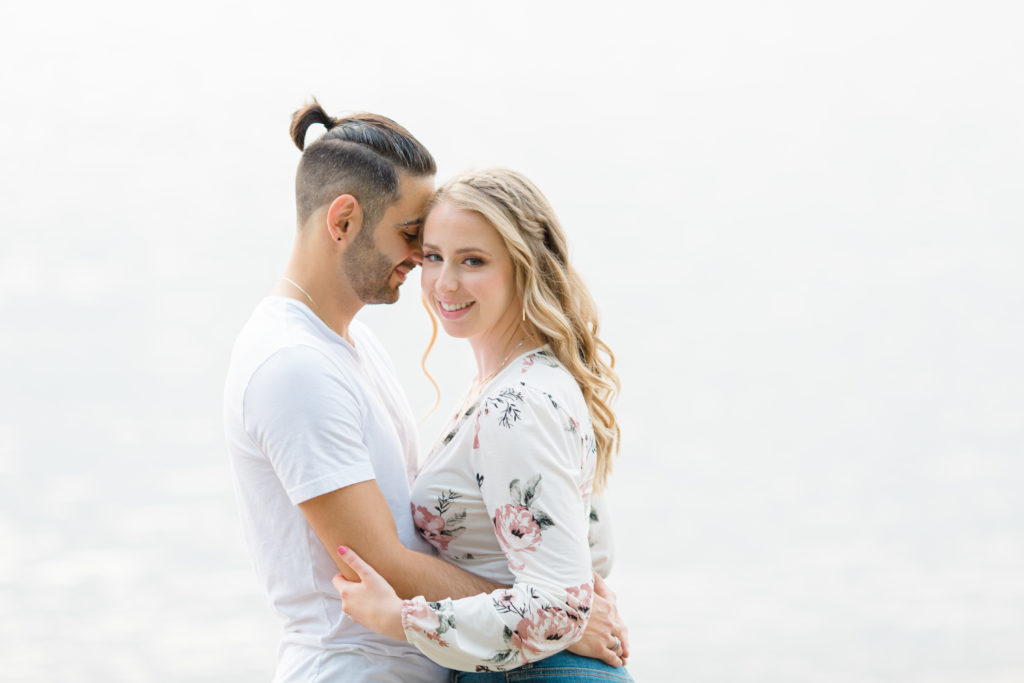 Cute Poses on the beach - Ideas for what to wear for Engagement Photography, Modern Engagement Session Inspiration Wardrobe Ideas. Unsure of what to wear for your engagement photos, we've got you! Romantic floral shirt & jeans.  White T-shirt & neutral pants . Boat Shoes and Fancy. beaded sandals. Engagement at Petrie Island, Orleans. Grey Loft Studio is Ottawa's Wedding and Engagement Photographer Videographer for Real couples, showcasing photos that are modern, bright, and fun.