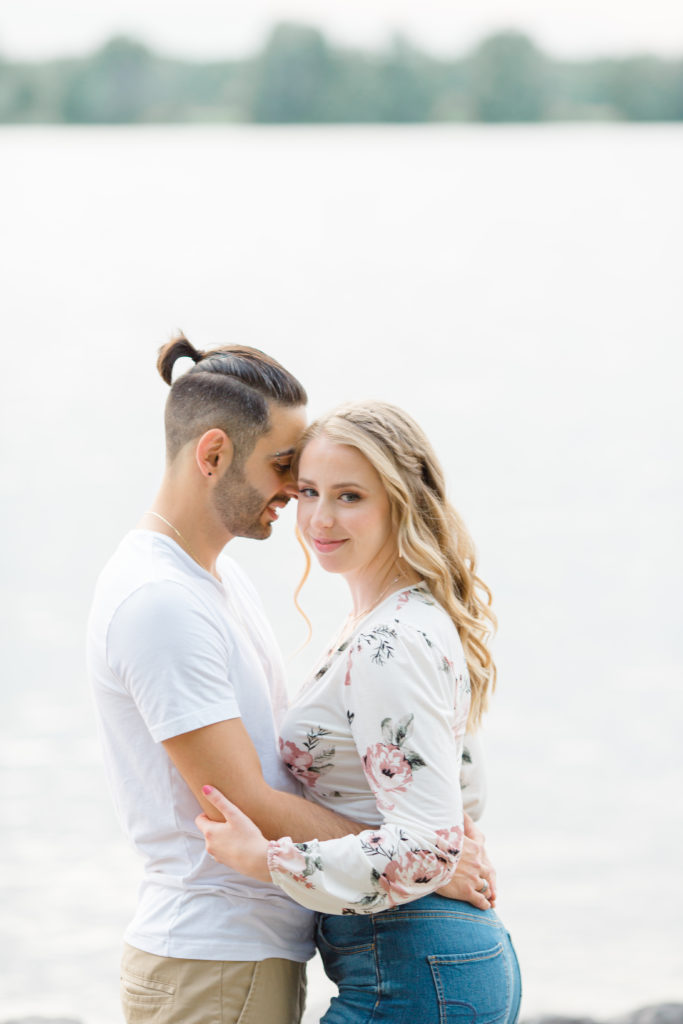 Cute Poses on the beach - Ideas for what to wear for Engagement Photography, Modern Engagement Session Inspiration Wardrobe Ideas. Unsure of what to wear for your engagement photos, we've got you! Romantic floral shirt & jeans.  White T-shirt & neutral pants . Boat Shoes and Fancy. beaded sandals. Engagement at Petrie Island, Orleans. Grey Loft Studio is Ottawa's Wedding and Engagement Photographer Videographer for Real couples, showcasing photos that are modern, bright, and fun.