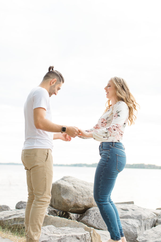 Cute Poses on the beach - Ideas for what to wear for Engagement Photography, Modern Engagement Session Inspiration Wardrobe Ideas. Unsure of what to wear for your engagement photos, we've got you! Romantic floral shirt & jeans.  White T-shirt & neutral pants . Boat Shoes and Fancy. beaded sandals. Engagement at Petrie Island, Orleans. Grey Loft Studio is Ottawa's Wedding and Engagement Photographer Videographer for Real couples, showcasing photos that are modern, bright, and fun.
