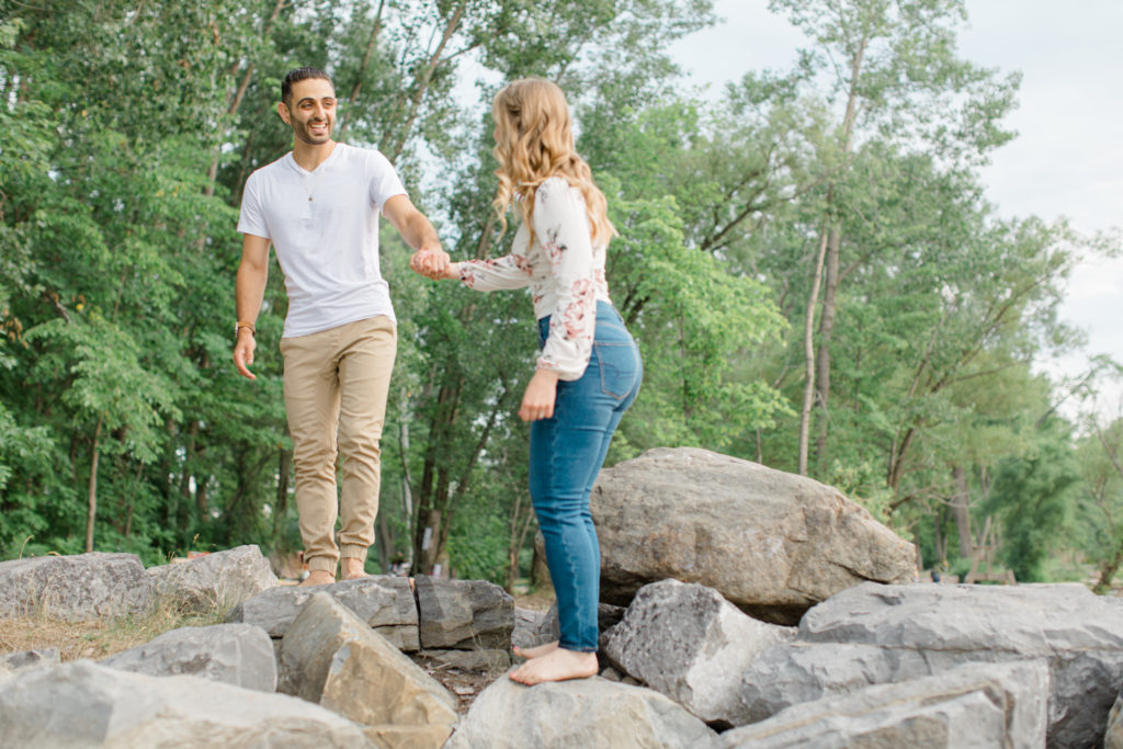 Cute Poses on the beach - Ideas for what to wear for Engagement Photography, Modern Engagement Session Inspiration Wardrobe Ideas. Unsure of what to wear for your engagement photos, we've got you! Romantic floral shirt & jeans.  White T-shirt & neutral pants . Boat Shoes and Fancy. beaded sandals. Engagement at Petrie Island, Orleans. Grey Loft Studio is Ottawa's Wedding and Engagement Photographer Videographer for Real couples, showcasing photos that are modern, bright, and fun.