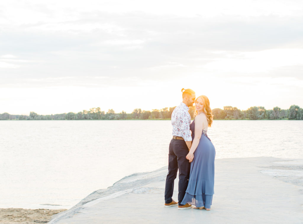Cute Poses on the beach - Ideas for what to wear for Engagement Photography, Modern Engagement Session Inspiration Wardrobe Ideas. Unsure of what to wear for your engagement photos, we've got you! Romantic floral shirt & jeans.  White T-shirt & neutral pants . Boat Shoes and Fancy. beaded sandals. Engagement at Petrie Island, Orleans. Grey Loft Studio is Ottawa's Wedding and Engagement Photographer Videographer for Real couples, showcasing photos that are modern, bright, and fun.