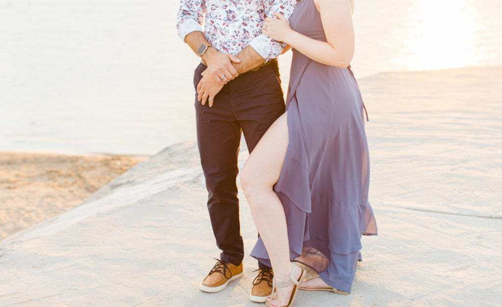 Cute Poses on the beach - Ideas for what to wear for Engagement Photography, Modern Engagement Session Inspiration Wardrobe Ideas. Unsure of what to wear for your engagement photos, we've got you! Romantic floral shirt & jeans.  White T-shirt & neutral pants . Boat Shoes and Fancy. beaded sandals. Engagement at Petrie Island, Orleans. Grey Loft Studio is Ottawa's Wedding and Engagement Photographer Videographer for Real couples, showcasing photos that are modern, bright, and fun.