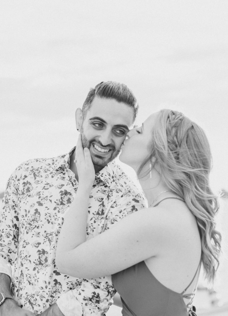 Cute Poses on the beach - Ideas for what to wear for Engagement Photography, Modern Engagement Session Inspiration Wardrobe Ideas. Unsure of what to wear for your engagement photos, we've got you! Romantic floral shirt & jeans.  White T-shirt & neutral pants . Boat Shoes and Fancy. beaded sandals. Engagement at Petrie Island, Orleans. Grey Loft Studio is Ottawa's Wedding and Engagement Photographer Videographer for Real couples, showcasing photos that are modern, bright, and fun.