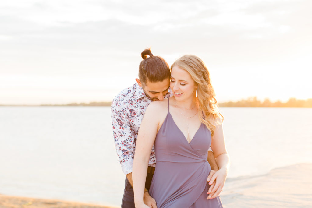 Cute Poses on the beach - Ideas for what to wear for Engagement Photography, Modern Engagement Session Inspiration Wardrobe Ideas. Unsure of what to wear for your engagement photos, we've got you! Romantic floral shirt & jeans.  White T-shirt & neutral pants . Boat Shoes and Fancy. beaded sandals. Engagement at Petrie Island, Orleans. Grey Loft Studio is Ottawa's Wedding and Engagement Photographer Videographer for Real couples, showcasing photos that are modern, bright, and fun.