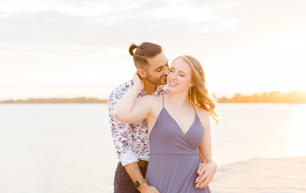 Cute Poses on the beach - Ideas for what to wear for Engagement Photography, Modern Engagement Session Inspiration Wardrobe Ideas. Unsure of what to wear for your engagement photos, we've got you! Romantic floral shirt & jeans.  White T-shirt & neutral pants . Boat Shoes and Fancy. beaded sandals. Engagement at Petrie Island, Orleans. Grey Loft Studio is Ottawa's Wedding and Engagement Photographer Videographer for Real couples, showcasing photos that are modern, bright, and fun.