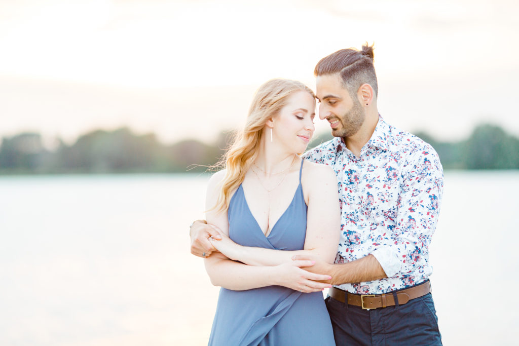 Cute Poses on the beach - Ideas for what to wear for Engagement Photography, Modern Engagement Session Inspiration Wardrobe Ideas. Unsure of what to wear for your engagement photos, we've got you! Romantic floral shirt & jeans.  White T-shirt & neutral pants . Boat Shoes and Fancy. beaded sandals. Engagement at Petrie Island, Orleans. Grey Loft Studio is Ottawa's Wedding and Engagement Photographer Videographer for Real couples, showcasing photos that are modern, bright, and fun.