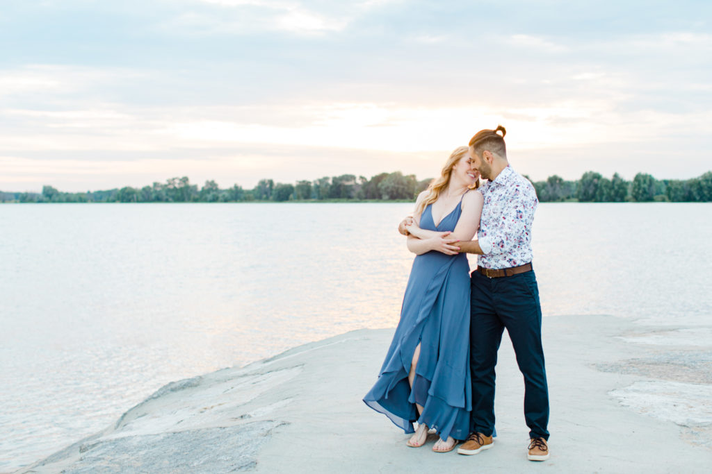 Cute Poses on the beach - Ideas for what to wear for Engagement Photography, Modern Engagement Session Inspiration Wardrobe Ideas. Unsure of what to wear for your engagement photos, we've got you! Romantic floral shirt & jeans.  White T-shirt & neutral pants . Boat Shoes and Fancy. beaded sandals. Engagement at Petrie Island, Orleans. Grey Loft Studio is Ottawa's Wedding and Engagement Photographer Videographer for Real couples, showcasing photos that are modern, bright, and fun.