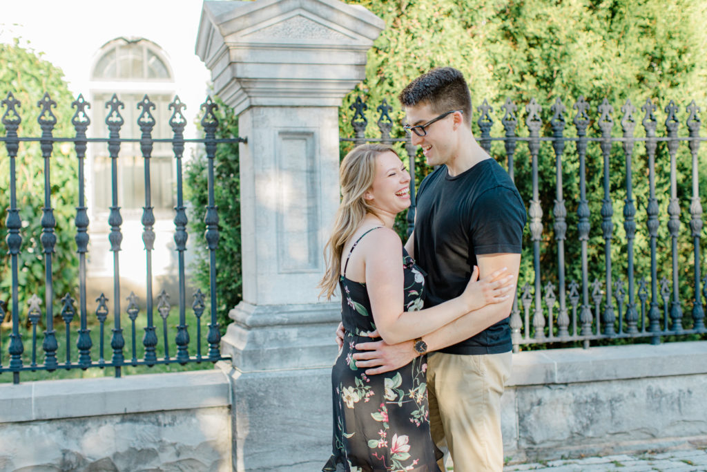 Laughing while posing at Rideau Hall - Ideas for what to wear for Engagement Photography, Modern Engagement Session Inspiration Wardrobe Ideas. Unsure of what to wear for your engagement photos, we've got you! Romantic floral dress. Black Polo T-shirt & neutral pants . Boat Shoes and Fancy beaded wedges. Engagement downtown Ottawa. Grey Loft Studio is Ottawa's Wedding and Engagement Photographer Videographer for Real couples, showcasing photos that are modern, bright, and fun.