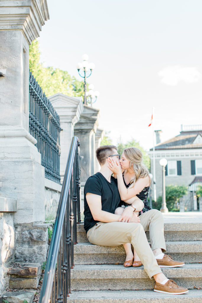 Cute couple Posing while sitting on steps at Rideau Hall - Ideas for what to wear for Engagement Photography, Modern Engagement Session Inspiration Wardrobe Ideas. Unsure of what to wear for your engagement photos, we've got you! Romantic floral dress. Black Polo T-shirt & neutral pants . Boat Shoes and Fancy beaded wedges. Engagement downtown Ottawa. Grey Loft Studio is Ottawa's Wedding and Engagement Photographer Videographer for Real couples, showcasing photos that are modern, bright, and fun.