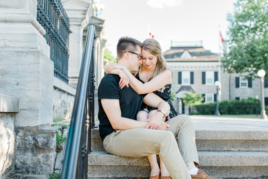 Cute couple Posing while sitting on steps at Rideau Hall - Ideas for what to wear for Engagement Photography, Modern Engagement Session Inspiration Wardrobe Ideas. Unsure of what to wear for your engagement photos, we've got you! Romantic floral dress. Black Polo T-shirt & neutral pants . Boat Shoes and Fancy beaded wedges. Engagement downtown Ottawa. Grey Loft Studio is Ottawa's Wedding and Engagement Photographer Videographer for Real couples, showcasing photos that are modern, bright, and fun.