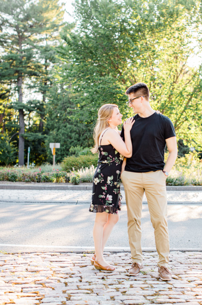 Cute Posing for Tall guys with short girls - Holding Hands Shot - Engagement Photo Poses- Posing while at Rideau Hall - Ideas for what to wear for Engagement Photography, Modern Engagement Session Inspiration Wardrobe Ideas. Unsure of what to wear for your engagement photos, we've got you! Romantic floral dress. Black Polo T-shirt & neutral pants . Boat Shoes and Fancy beaded wedges. Engagement downtown Ottawa. Grey Loft Studio is Ottawa's Wedding and Engagement Photographer Videographer for Real couples, showcasing photos that are modern, bright, and fun.