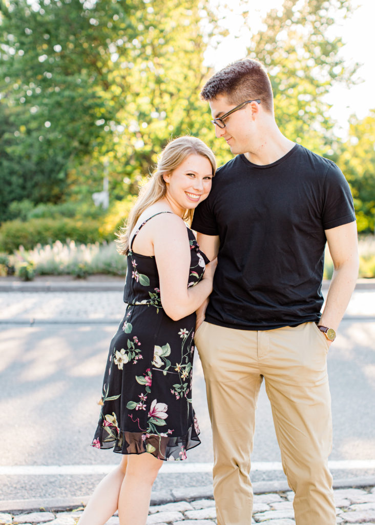 Cute Posing for Tall guys with short girls - Holding Hands Shot - Engagement Photo Poses- Posing while at Rideau Hall - Ideas for what to wear for Engagement Photography, Modern Engagement Session Inspiration Wardrobe Ideas. Unsure of what to wear for your engagement photos, we've got you! Romantic floral dress. Black Polo T-shirt & neutral pants . Boat Shoes and Fancy beaded wedges. Engagement downtown Ottawa. Grey Loft Studio is Ottawa's Wedding and Engagement Photographer Videographer for Real couples, showcasing photos that are modern, bright, and fun.