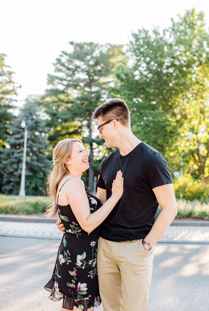 Cute Posing for Tall guys with short girls - Holding Hands Shot - Engagement Photo Poses- Posing while at Rideau Hall - Ideas for what to wear for Engagement Photography, Modern Engagement Session Inspiration Wardrobe Ideas. Unsure of what to wear for your engagement photos, we've got you! Romantic floral dress. Black Polo T-shirt & neutral pants . Boat Shoes and Fancy beaded wedges. Engagement downtown Ottawa. Grey Loft Studio is Ottawa's Wedding and Engagement Photographer Videographer for Real couples, showcasing photos that are modern, bright, and fun.