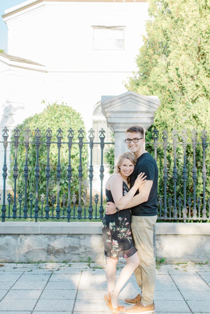 Smiling at the Camera - Ideas for what to wear for Engagement Photography, Modern Engagement Session Inspiration Wardrobe Ideas. Unsure of what to wear for your engagement photos, we've got you! Romantic floral dress. Black Polo T-shirt & neutral pants . Boat Shoes and Fancy beaded wedges. Engagement downtown Ottawa. Grey Loft Studio is Ottawa's Wedding and Engagement Photographer Videographer for Real couples, showcasing photos that are modern, bright, and fun.