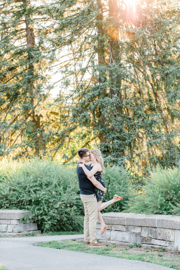 Lift & Kick pose - Cute Posing for Tall guys with short girls - Holding Hands Shot - Engagement Photo Poses- Posing while at Rideau Hall - Ideas for what to wear for Engagement Photography, Modern Engagement Session Inspiration Wardrobe Ideas. Unsure of what to wear for your engagement photos, we've got you! Romantic floral dress. Black Polo T-shirt & neutral pants . Boat Shoes and Fancy beaded wedges. Engagement downtown Ottawa. Grey Loft Studio is Ottawa's Wedding and Engagement Photographer Videographer for Real couples, showcasing photos that are modern, bright, and fun.