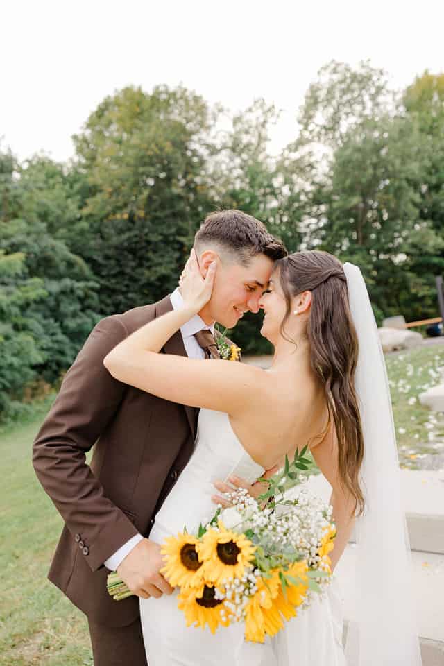 Bride and groom embracing among apple trees at 1818 Farm and Cidery in Ottawa