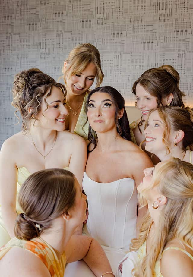Bride and bridesmaids laughing together while getting ready for their wedding at Brookstreet Hotel in Kanata