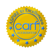 A gold, circular seal with blue stars and text that reads "ASPIRE to Excellence® CARF ACCREDITED.