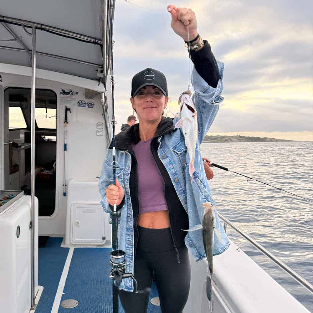 a woman holding a fish she caught Deep sea fishing in the south coast near Narooma