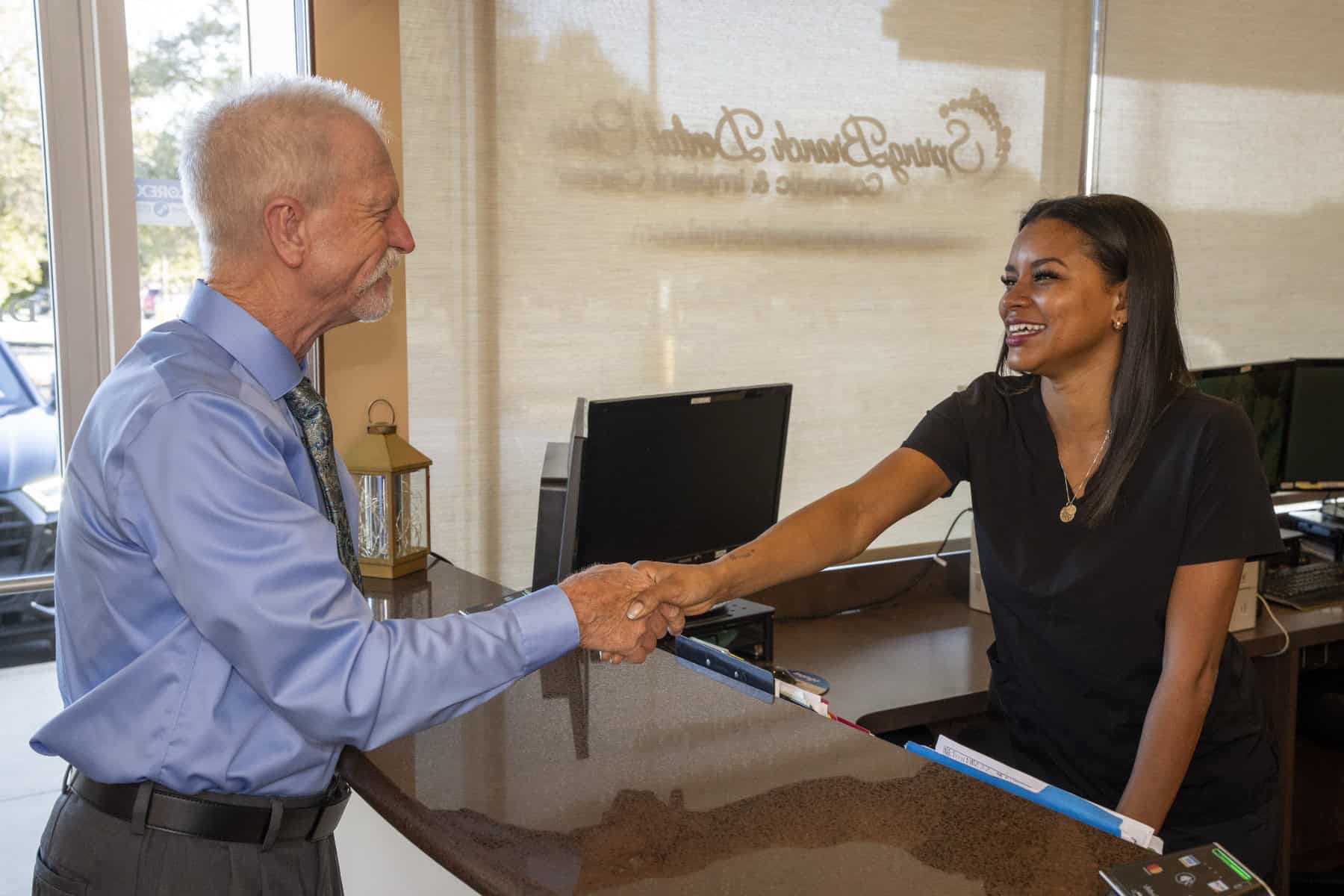 A patient and a dental assistant shaking hands