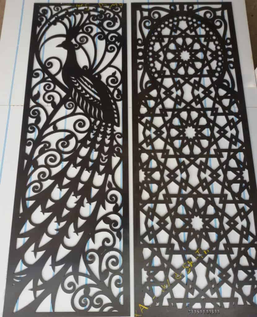 Intricate black metal decorative panels featuring a peacock and geometric patterns.