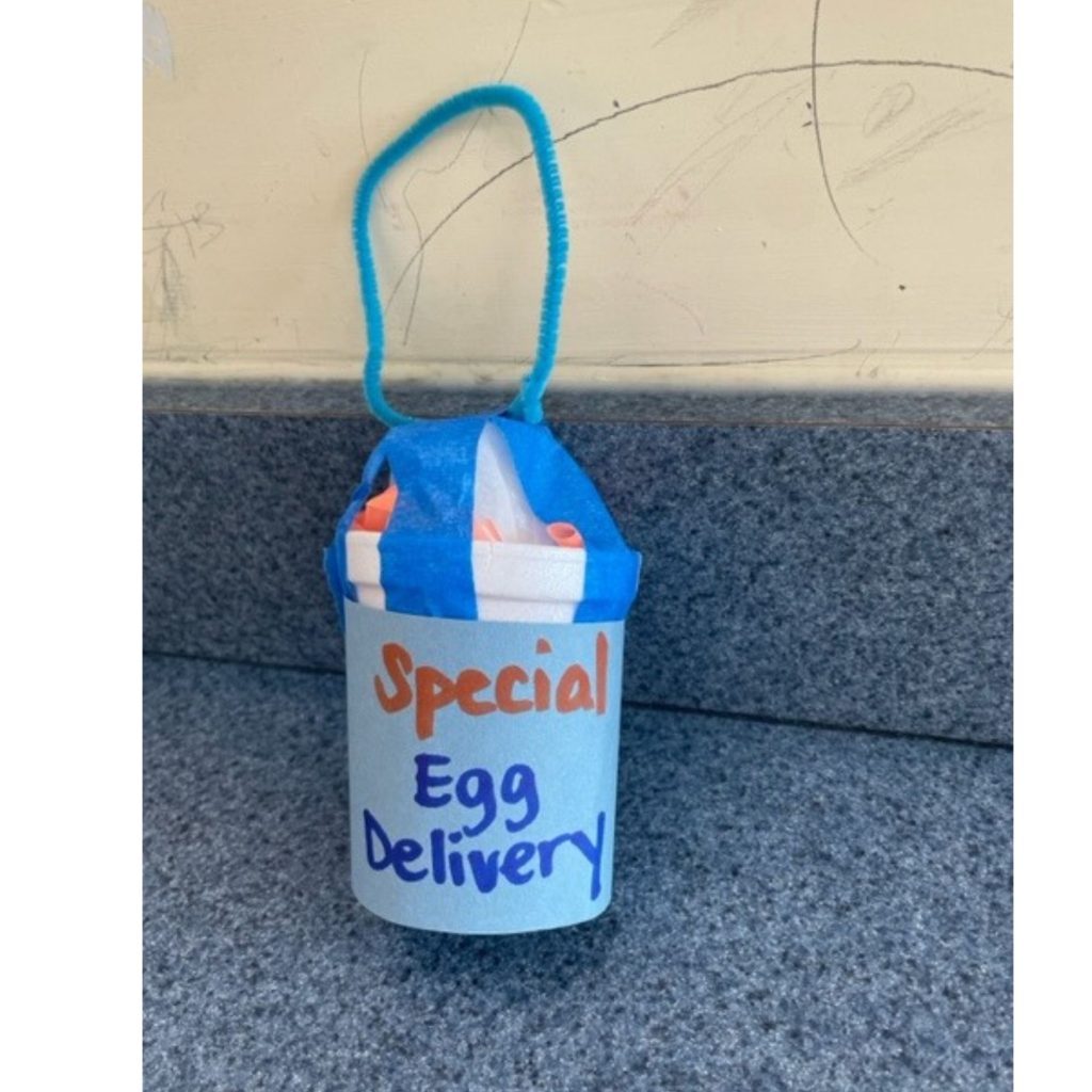 This image shows an egg drop package created from a styrofoam cup, pipe cleaner, straws, tape, and construction paper. The side of the cup says "Special Egg Delivery."