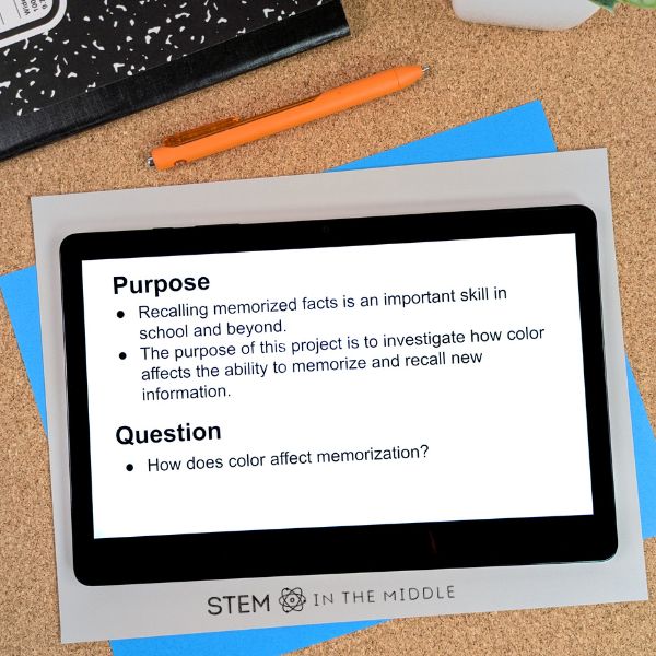 This image shows a tablet. On the tablet is a document where a student has recorded the purpose and question for their science fair project. A composition notebook and pen are pictured in the background.
