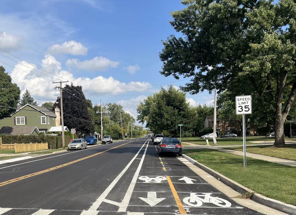 A wide bike lane on a suburban Chicago street with clear signage and parking.