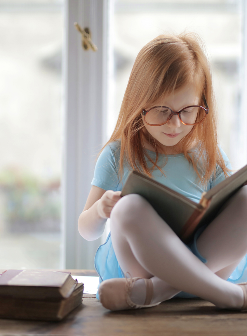 Young girl with ginger hair reading a book
