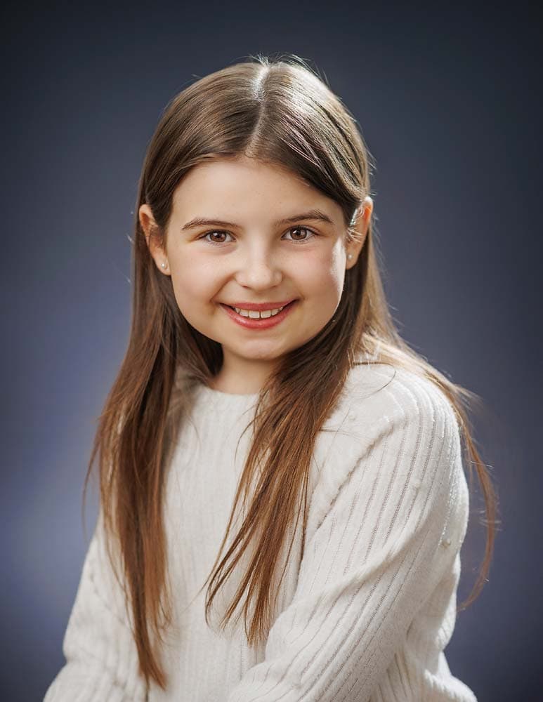 Children’s Headshots in Sussex. Professional headshot of a young girl with long brown hair smiling, Sussex Headshots, high-quality business portrait photography in Sussex, perfect for corporate and personal branding.
