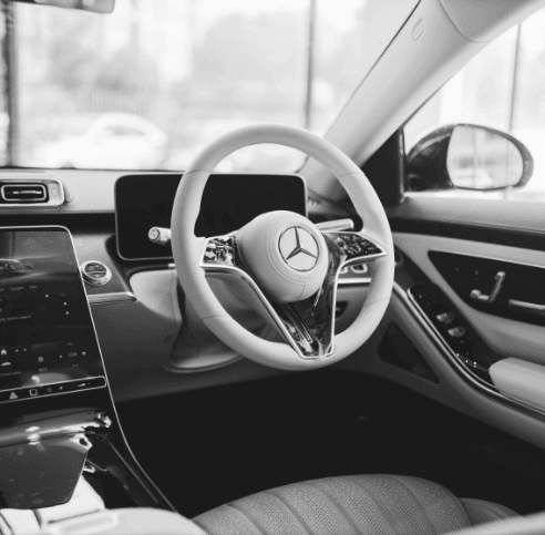 Interior view of a luxury economy car featuring a sleek dashboard and Mercedes-Benz steering wheel.