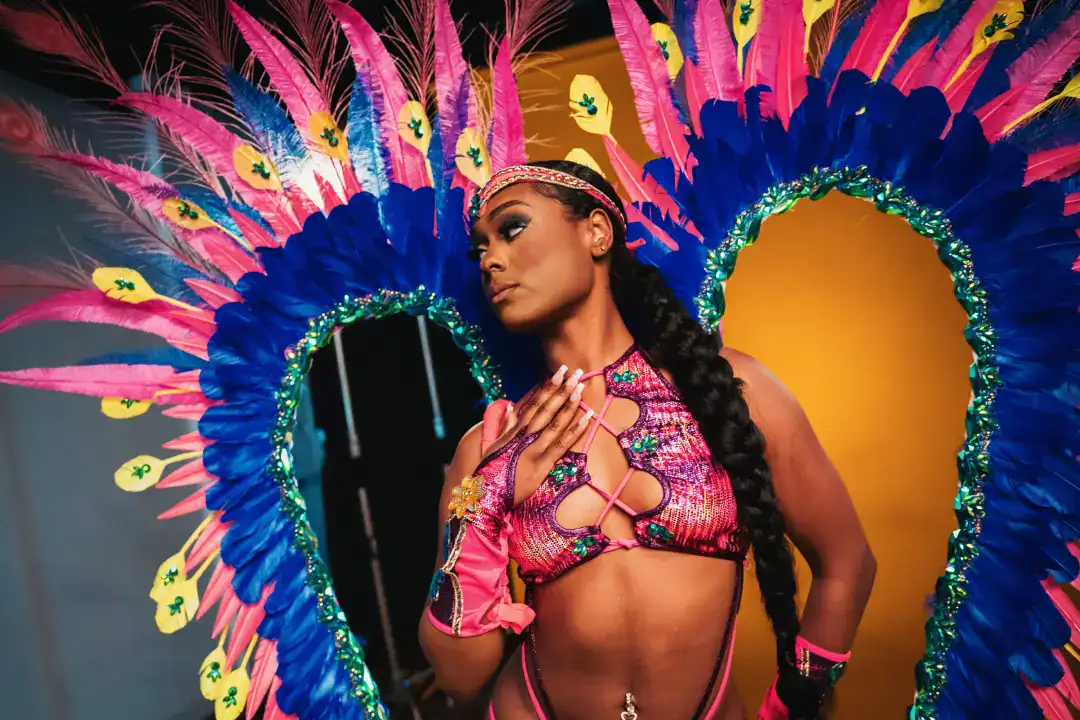 Vibrant woman in colorful carnival costume with large feathered headdress, elaborate designs, and sparkling accessories, showcasing festive celebration, dance, and cultural artistry.