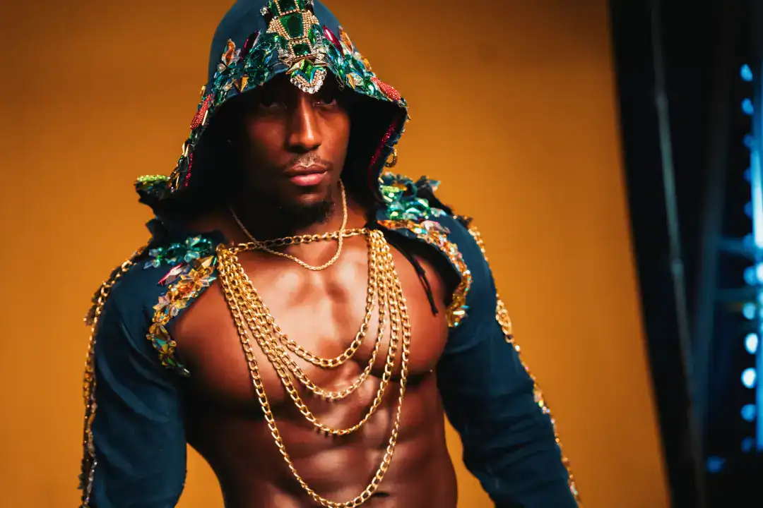 Luxurious fashion model wearing embellished hoodie with gold chains and jewelry, showcasing high-end urban style and streetwear fashion photography.