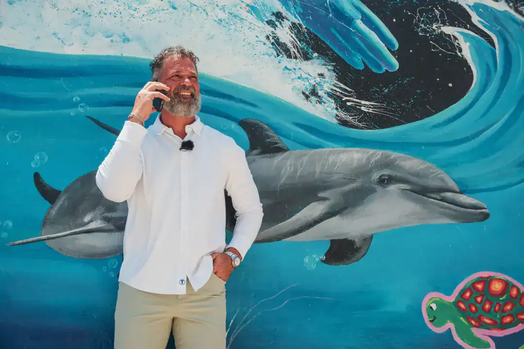 Dolphin and man on phone at Syslo Ventures corporate event, marine-themed backdrop, professional branding, business networking, ocean conservation focus, innovative environmental solutions, engaging corporate environment, marine life imagery, water-themed event decor, eco-conscious business branding, oceanic design elements, sustainable business practices, inspiring leadership in marine ecosystems.
