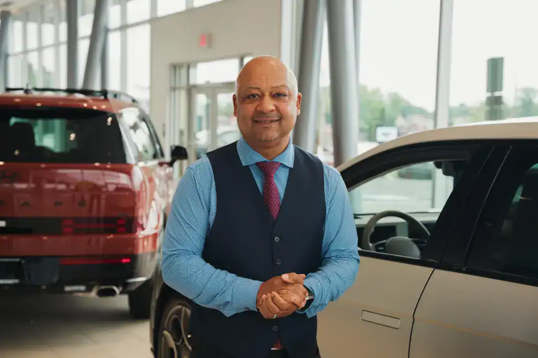 Professional man in a car dealership, showcasing automotive sales services, representing trusted vehicle purchasing and financing options.