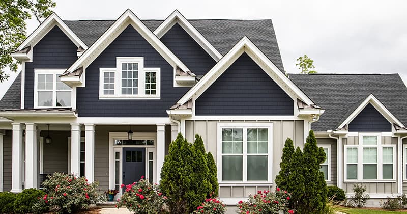 Blue and white house exterior with modern architectural design and lush landscaping.