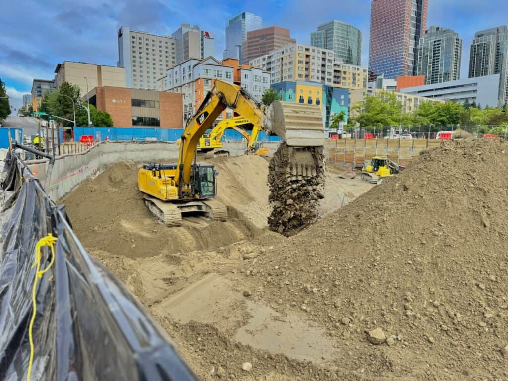Team Nelson excavator moving material for export during deep excavation for underground parking at Broadstone Bellevue in Bellevue, WA.