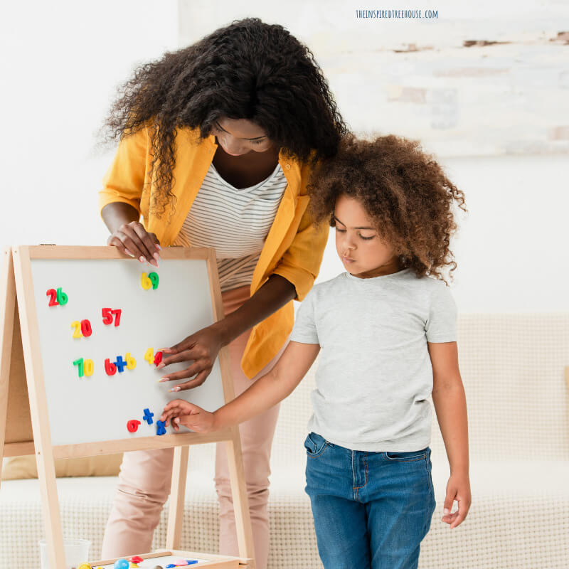 School based occupational therapist assisting child with moving magnets on an easel