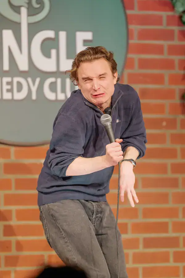 Comedian acting out a joke on stage at The Jungle Comedy Club