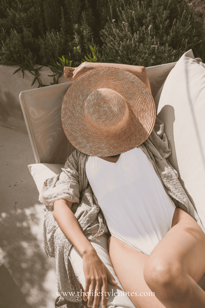 A Few Things I'm Loving: August Edition. Woman lounging on chair outdoors with bathing suit and straw hat.