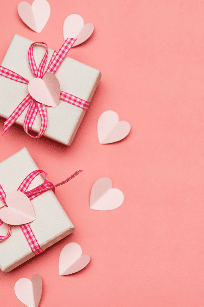 Simple ways to make Valentine's Day special for your kids. Valentine gifts wrapped in pink and white ribbon with paper hearts.