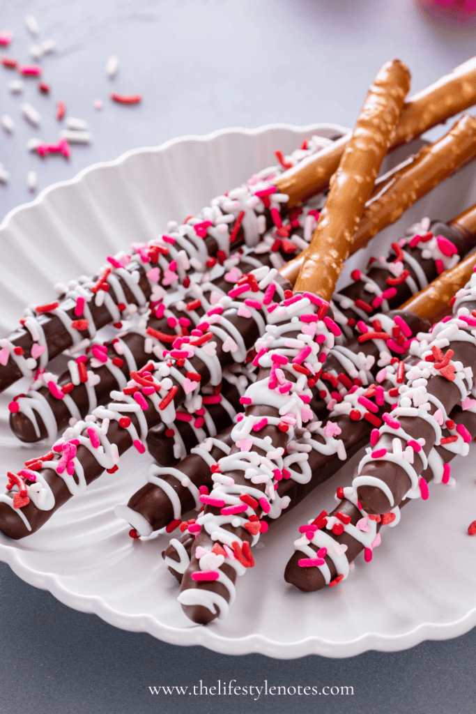 Cute and Easy Valentine's Day Treat Ideas for Kids. White plate with chocolate covered pretzel rods with pink, red, and white sprinkles.